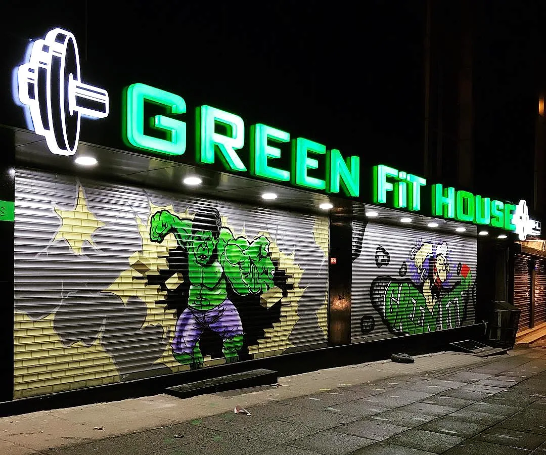 Green Fit House'un gece görünümü: neon tabela ve kepenk üzerindeki grafiti